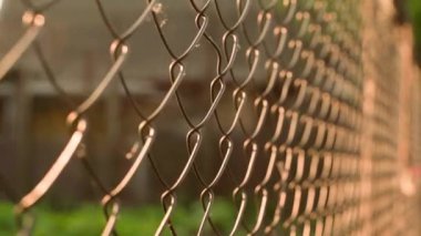Camera movement along the chain-link fence illuminated by the morning dawn sun. High quality FullHD footage