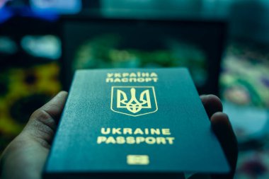 Ukrainian biometric passport in hand close-up in cold blue colors