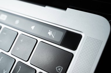 Kiev, Ukraine - August 9,2022: Silent mode sign on touch bar apple macbook pro close up. Fingerprint sensor next to the volume buttons on the touchpad of the laptop