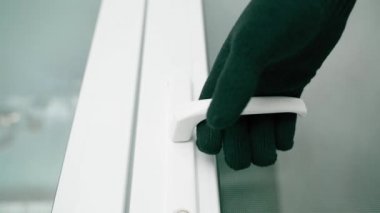 A hand in a black glove slowly pulls the handle of a white plastic door and opens it. Perspective view from below. High quality FullHD footage