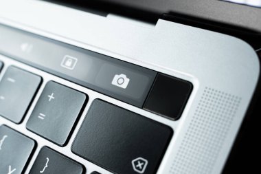 Kiev, Ukraine - August 9, 2022: camera pictogram meaning screen shot on touch bar apple macbook pro close up. Fingerprint sensor next to screen recording buttons on laptop touchpad