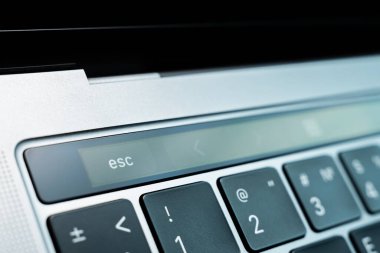 Kiev, Ukraine - August 9, 2022: Esc button on touch bar apple macbook pro closeup. Touch escape button on a modern laptop