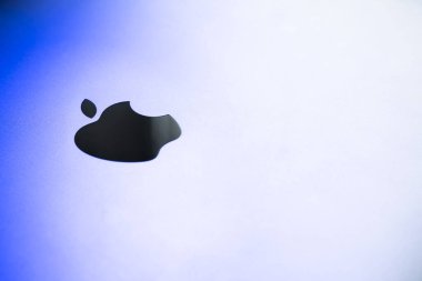 Kiev, Ukraine - August 9, 2022: top cover of macbook pro with apple mirror logo close up. Brushed aluminum laptop case in blue lighting
