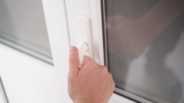 A hand pulls on the handle of the white plastic doors, unsuccessfully. Attempt to open frozen doors by force. Close-up, slow motion. High quality FullHD footage