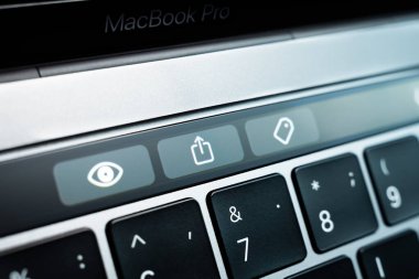 Kiev, Ukraine - August 9,2022: Button symbolizing file upload and sharing on touch bar apple macbook pro close up. Additional small touch screen on a gray laptop