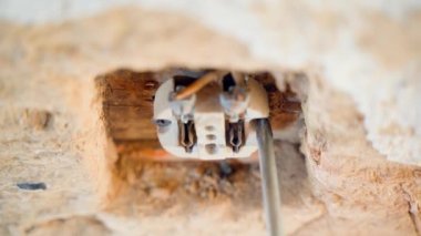 Electrical wall outlet repair. A screwdriver unscrews the ceramic body of an ancient socket close-up, top view. High quality 4k footage