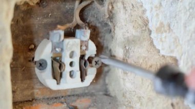 Twisting the ceramic body of a wall electrical outlet close-up. Repair of obsolete electrics in an old house. High quality 4k footage