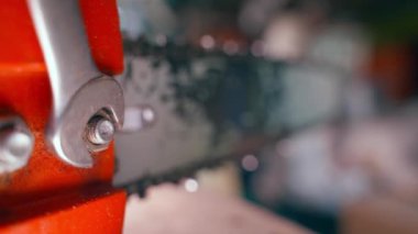 Unscrewing the chainsaw body nut with a wrench and fingers close-up. Chainsaw chain replacement and tensioning. Maintenance of household gasoline appliances according to the plan. High quality 4k