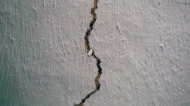 A crack in the white clay wall of an old house. Camera movement along the crack in the ceiling close-up. Loss of building integrity. High quality FullHD footage