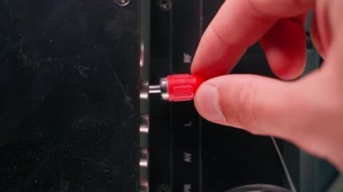 Hand inserts rca connectors of red white and yellow color from tv. Plug tulip of the old generation close-up. Wires for transmitting audio and video signals are thin, poor quality. High quality 4k