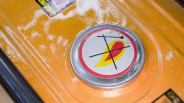 A hand unscrews the filler cap of an orange gas tank close-up. Refueling a gasoline generator. Canister lid with flammable content sign. High quality 4k footage