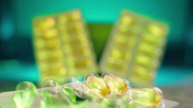 Launched blister with fish oil capsules. Packaging with gelatin capsules with omega 3 and omega 6 close-up in the foreground. Iridescent multi-colored lighting. High quality 4k footage