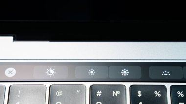 Kiev, Ukraine - August 9,2022: Buttons for adjusting screen brightness and switching night mode and True Tone function on touch bar apple macbook pro close up. Modern stylish gray laptop