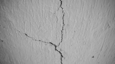 Eski bir çiftlik evinin çatlamış tavanının dramatik siyah beyaz videosu. Patlamadan ya da depremden sonra baş dönmesi. Beyaz kil tavanda çatlak, yakın plan, alt manzara. Yüksek kalite