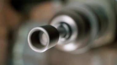 A close-up hexagon socket on a screwdriver is spinning in a drill chuck against a blurred background. Nozzle for loosening nuts on a wrench. High quality FullHD footage