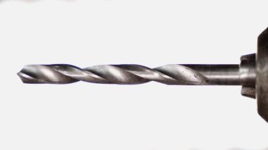 A drill for metal and wood close-up is spinning on a white background. The screwdriver chuck holds a sharp, shiny metal drill. Metal rod as a tool for making holes. High quality 4k footage