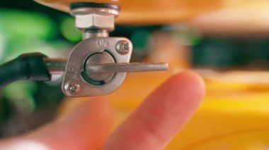 The hand opens the fuel supply valve from the tank to the engine carburetor close-up. Restoration of fuel supply and export of oil industry raw materials. Permission to cooperate and use gasoline