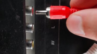 Hand inserts rca connectors of red white and yellow color from tv. Plug tulip of the old generation close-up. Wires for transmitting audio and video signals are thin, poor quality. High quality 4k