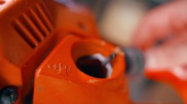 Bir el, turuncu elektrikli testerenin gri plastik yakıt dolgu kapağını büker. Bahçe aletlerini dolduruyorum. Yakıt yağı karışımı sembolü. Yüksek kalite 4k görüntü