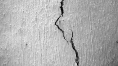 Kırsal kesimde eski bir evin beyaz tavanında uzun bir çatlak. Kamera kil duvardaki bir çatlak boyunca hareket ediyor. Konutun hızla yok edilmesi ve bütünlük kaybı. Depremden sonra