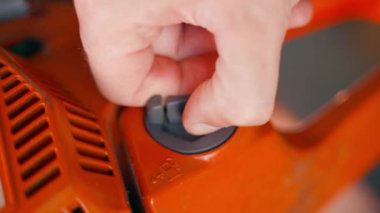 Bir el, turuncu elektrikli testerenin gri plastik yakıt dolgu kapağını söker. Bahçe aletlerini dolduruyorum. Yakıt yağı karışımı sembolü. Yüksek kalite 4k görüntü