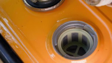 Fuel is poured into the fuel tank of a yellow gas generator from a plastic canister close-up. Refueling a gasoline generator. A jet of clear clean gasoline into the filler neck. High quality 4k