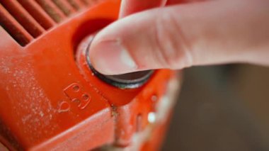El, zincir yağlama için yağ deposunu kapatıyor. Elektrikli testerenin turuncu gövdesinde yağlama sembolü var. Yağ dolgusu boynu plastik kapakla kapatılmış. Yüksek