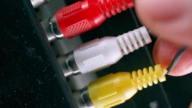 El, televizyondaki kırmızı-beyaz ve sarı rca bağlantılarını çekiyor. Eski neslin yakın plan lalesi. Ses ve video sinyalleri iletmek için kablolar zayıf, kalitesiz. Yüksek kalite 4k