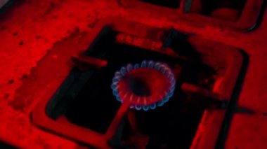 Eski bir gaz ocağında güvenlik önlemi olmadan yanan bir yangın polis ışıklarını yakıyor. Eski kirli ve paslı mutfak gaz sobası. Yanan mavi yakıt yakınında düzgün bir kamera hareketi. Yüksek kalite FullHD