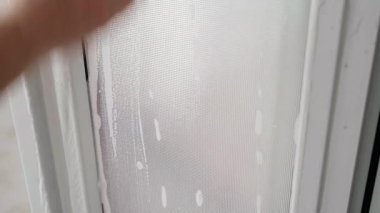 Bir el, sabunlu suyla kaplanmış bir süngerle plastik bir kapının opak penceresini yıkıyor. Işıl ışıl iç kısımların zevkli temizliği. Ev kadınının ev işi. Köpük deterjanı. Yüksek kalite 4k