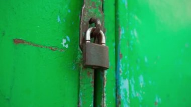 Küçük bir asma kilit demir yeşil bir garaj kapısına asılmış. Pürüzsüz kamera hareketi. Anahtarsız kilitli kapılar. Eski depo kilitli. Yüksek kaliteli FullHD görüntüler