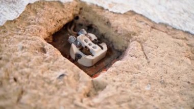 Kırsal bir evin kil duvarında seramik tabanlı eski sökülmüş elektrik prizi. Pürüzsüz kamera dönüşü. Eski duvar prizlerinin yapısı. Eski bir binada tadilat. Yüksek