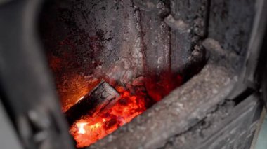 Bir el, bir evi ısıtmak için katı bir yakıt kazanının ocağına odun atar. Kalorifer ocağında yangın ve yakıt atmaktan kıvılcımlar. Soğuk kış mevsiminde odanın ısıtılması. Yüksek