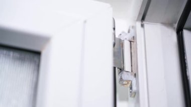 Plastik kapının menteşesi yakın plan. Plastik pencere ve kapıları açıp kapama mekanizması. Kapı tesisatının onarımı ve bakımı. Sürtünme giysisi ve parça yağlama. Yüksek kalite 4k