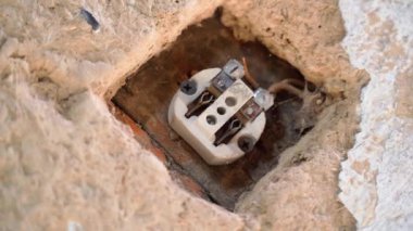 Kırsal bir evin kil duvarında seramik tabanlı eski sökülmüş elektrik prizi. Pürüzsüz kamera dönüşü. Eski duvar prizlerinin yapısı. Eski bir binada tadilat. Yüksek