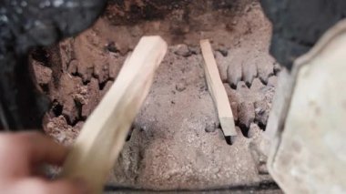 Katı bir yakıt kazanının şömine kutusunda ateş yakmak için odun parçaları istifleyen bir el. Kışın bir köylünün sabah rutini. Soğuk mevsimde özel bir evi ısıtmak. Yüksek kalite 4k