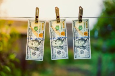300 dolarlık banknotlar çamaşır kurutma makinesine asılıydı. Arka planda çamaşır mandalları vardı. Küçük çaplı para aklama. Yasadışı para alımı için yolsuzluk şeması