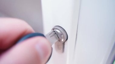 Bir el plastik kapıların anahtar deliğine delinmiş bir anahtar yerleştiriyor, çeviriyor ve çıkarıyor. Yakından, yukarıdan, beyaz kapıların girişinin kilidinden görülebiliyor. Bir odayı kapatmak ya da açmak