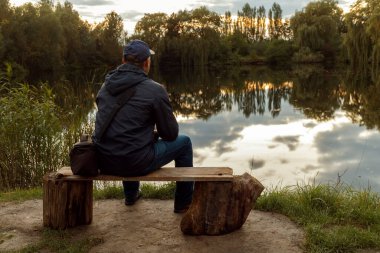 A man sitting in front of a lake.