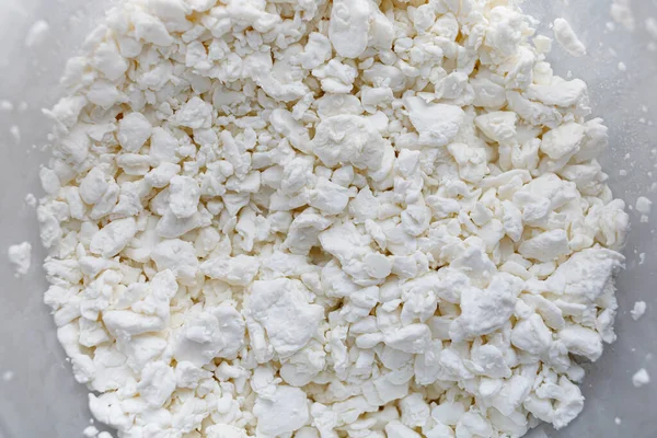 White cottage cheese in a bucket. Grainy cheese close-up