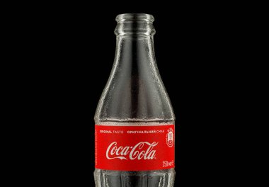 LVIV, UKRAINE - October 13, 2021: Coca cola empty bottle on black background