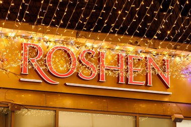 LVIV, UKRAINE - December 26, 2021: Roshen shop sign at night.