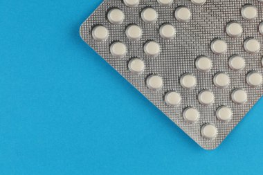 Pills in a blister on blue background. place for text cope space