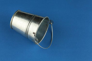 Empty metal bucket on a blue background