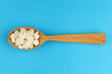 White medical round pills in a spoon