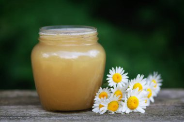 Honey in a jar on the pass. Jar of honey with flowers