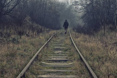 A lone man passing by walks on a track in the fog