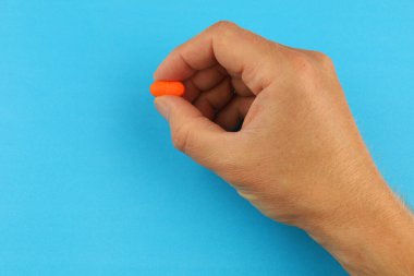 Orange pill in hand close-up