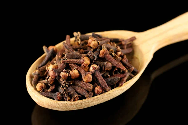 Clove spice in a wooden spoon. A spice of dried cloves lies on a wooden spoon