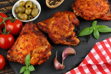 Chicken thighs baked with vegetables and spices. Delicious and appetizing food on the table.